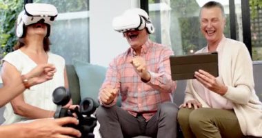 VR kulaklıklar takıyor, kıdemli arkadaşlar gülüyor ve sanal gerçeklik deneyiminin tadını çıkarıyor. Teknoloji, VR oyun, arkadaşlık, eğlence, eğlence, yaşlılar