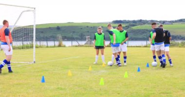Erkek ve kadın futbolcular topun peşinden koşuyor ve sahada koçla külahlardan kaçıyorlar. spor, yaşam tarzı, takım çalışması, futbol ve etkinlik.