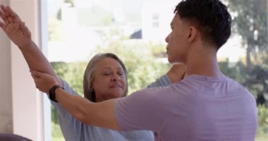 Kol egzersizlerinde yaşlı bir kadına yardımcı olmak, erkek fizyoterapist rehberlik hareketleri. Fizyoterapi, rehabilitasyon, sağlık, kıdemli bakım, fizik tedavi, rehberlik