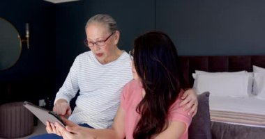 Tablet kullanarak, Asyalı büyükanne ve torun oturma odasında önemli konuları tartışıyorlar. Aile, çok nesilli, teknoloji, iletişim, bağlanma, sohbet