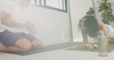 Birlikte egzersiz yapıyorlar, çok ırklı çiftler evlerinde yoga minderleri üzerinde kalas egzersizi yapıyorlar. Spor, egzersiz, ev çalışması, takım çalışması, sağlıklı yaşam tarzı, birliktelik.
