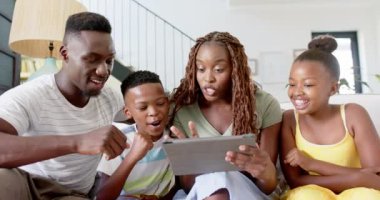 Afro-Amerikan anne evde babasına, oğluna ve kızına tablet gösteriyor. Aile, teknoloji, ebeveynlik, bağlılık, birliktelik, çocuklar, değişmemiş, yavaş çekim