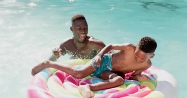 Baba ve oğul şişme şamandırayla bilardo oynuyorlar, yaz gününün tadını çıkarıyorlar. Aile, açık hava, eğlence, eğlence, değiştirilmemiş, yavaş çekim