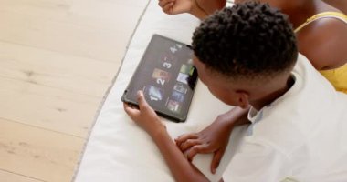 Afro-Amerikan erkek ve kız kardeşler eğitim oyunları için tablet kullanıyorlar, evde birlikte öğreniyorlar. Teknoloji, çocuklar, evde eğitim, dijital, öğrenim, çocukluk