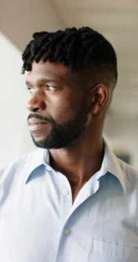 Dikey video: Elbise gömlekli bir adam profesyonel ortamda kameraya özgüvenle bakıyor. İş, yürütme, şirket, girişimci, liderlik, resmi