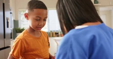 Sırt çantalı çocuğa yardım etmek, anne oğlunu mutfakta okula hazırlamak, sabah rutini, okul hazırlığı, Afro-Amerikan ailesi, çocukluk, bağ kurmak..