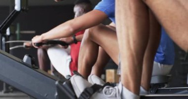 Kürek makineleri üzerinde egzersiz yapmak, erkekler spor salonunda birlikte çalışmak. Spor, egzersiz, egzersiz, antrenman, takım çalışması, güç