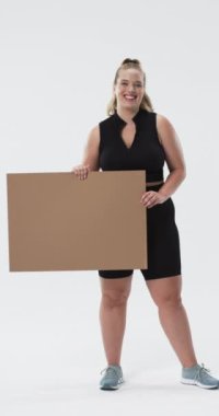 Dikey video: Esneyen kol ve gülümseme, artı boş karton tabela tutan boyunda bir kadın. Güven, güç, güç, boşluk işareti, boşluk boşluk, neşeli
