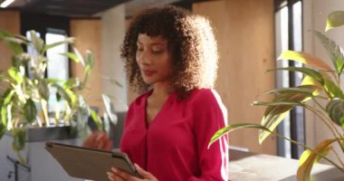 Tablet kullanan, kırmızı bluzlu bir kadın modern ofis ortamında çalışıyor. Teknoloji, iş, meslek, çalışma alanı, şirket, üretkenlik