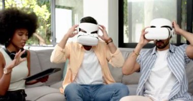 VR kulaklıkları kullanarak, farklı arkadaşlar kanepenin üzerinde sanal gerçekliği deneyimlediler. Teknoloji, eğlence, oyun, sürükleyici, eğlence, eğlence