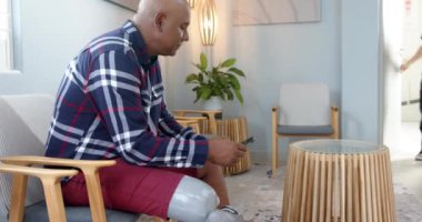 Ekose gömlekli bir adam protez laboratuvara giriyor. Önlüklü bir profesyonel tarafından karşılanıyor. Protezler, rehabilitasyon, sağlık hizmetleri, tıbbi, laboratuvar, selamlama