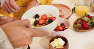 Birlikte kahvaltı ediyorlar, çok ırklı son sınıf çifti evde taze meyve ve ekmeğin tadını çıkarıyorlar. Beraberlik, sabah, evcil