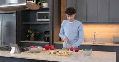 Sebze hazırlamak, evdeki modern mutfakta malzemeleri doğrayan genç bir adam. Aşçılık, aşçılık, yerli, yaşam tarzı, yemek hazırlama, yemek