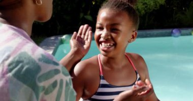 Anne ve kızı yüzme havuzuyla gülümsüyor ve birlikte oynuyorlar. Aile, mutluluk, bağlanma, yaz, boş zaman, açık hava, eğlence, değiştirilmemiş, yavaş çekim