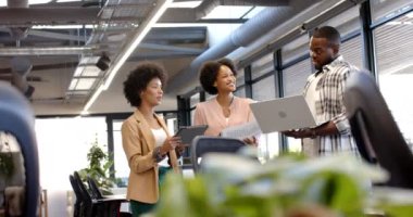 İşlerini tartışan profesyoneller dizüstü bilgisayar ve tableti ofiste tutuyorlar. İş, takım çalışması, beyin fırtınası, toplantı, modern ofiste büyük pencereli ve endüstriyel stil dekorlu bir başlangıç, değiştirilmemiş