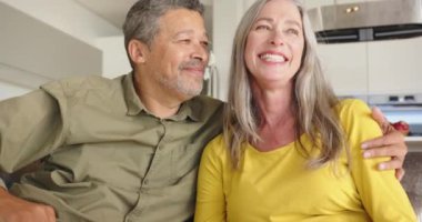 Koltukta oturmak, çok ırklı üst düzey çiftlerin el ele tutuşması ve evde dinlenmesi. Beraberlik, yaşam tarzı, rahatlama, bağlanma, konforlu, evcil