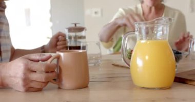 Fransız basınından bardağa kahve dolduruyor, kıdemli adam ortağıyla kahvaltı yapıyor. Günaydın, çift, arkadaşlık, yemek, konfor, içecek, değiştirilmemiş, yavaş çekim