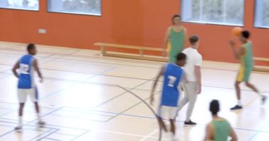 Spor salonunda basketbol oynayan çok ırklı erkek basketbolcular koç yürüyüşü ve gözlemleme oyunu oynuyorlar. spor, yaşam tarzı ve etkinlik.