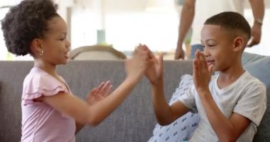 Afrikalı Amerikalı baba, küçük oğlu ve melez kızıyla oynuyor. Parlak, modern oturma odası yumuşak ışıklandırma ve rahat dekor ile sıcak atmosfer yaratıyor, değişmeden.