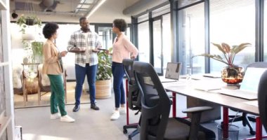 Modern, çeşitli bir ofis ortamında takım çalışmasını tartışan profesyoneller. Başlangıç fikirleri hakkında beyin fırtınası ve toplantı, değiştirilmemiş, yavaş çekim