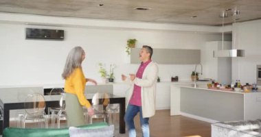 Birlikte dans ediyorlar, mutlu çok ırklı son sınıf çifti evdeki modern mutfakta eğleniyorlar. Yaşam tarzı, mutluluk, birliktelik, yemek pişirme, dans etme, neşe