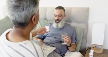 İlaç dağıtımı, bir bardak suyla yaşlı adamla ilgilenen bir kadın. Bakım, yaşlılık, sağlık, hemşirelik, yardım, şefkat