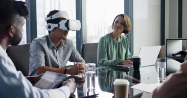 VR kulaklığı kullanarak, modern ofisteki iş arkadaşlarıyla iş görüşmesi yapan bir adam. Teknoloji, takım çalışması, işbirliği, yenilik, beyin fırtınası, şirket
