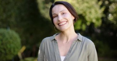 Doğanın tadını çıkarmak, dışarıda kameraya bakan gülümseyen bir kadın. Mutluluk, yaşam tarzı, portre, güneş ışığı, tasasız, neşeli