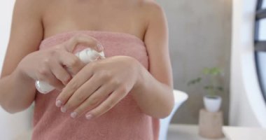 Losyon sürüyorum, havlu kadın banyoda cilt bakımına odaklanıyor. Hijyen, kendine bakım, güzellik, şımartma, nemlendirici, sağlık.