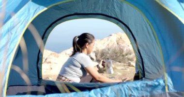 Dağlarda kamp yapmak, kadın çadırda kahve hazırlamak, açık hava macerasının tadını çıkarmak. Yürüyüş, açık hava, doğa, seyahat, rahatlama, boş zaman