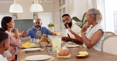 Afro-Amerikan ailesi birlikte yemek yiyor, yemek ve içecekleri yemek masasında dağıtıyor. Beraberlik, kutlama, paylaşma, bağlanma