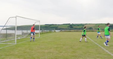 Erkek ve kadın futbolcular, kaleci pas veriyor ve sahada top peşinde koşan oyuncular. spor, yaşam tarzı, takım çalışması, futbol ve etkinlik.