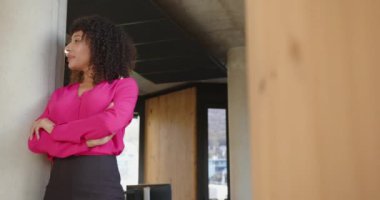 Pembe bluzlu, kendine güveni tam bir iş kadını ofiste kollarını kavuşturmuş duruyor. Güven, profesyonel, kurumsal, liderlik, güçlendirme, girişimci