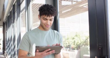 Modern iç tasarım ofisinde tablet kullanan gülümseyen adam teknolojinin tadını çıkarıyor. İş, dijital, profesyonel, çalışma alanı, yenilik