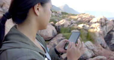 Dağlarda yürüyüş, kayalık arazide yol almak için akıllı telefon kullanan bir kadın. Macera, açık hava, gezinti, yürüyüş, teknoloji, keşif