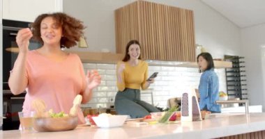 Mutfakta birlikte yemek pişirirken, üç kadın arkadaş yemek hazırlıyor ve sohbetten zevk alıyorlar. Arkadaşlar, yemek hazırlama, takım çalışması, aşçılık, eğlence, birliktelik.