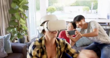 VR kulaklığı kullanan kadın, aile kayıtları akıllı telefonlarla yapılırken sanal gerçekliğin tadını çıkarıyor. teknoloji, müteahhit, keyif, eğlence, etkileşim, dijital