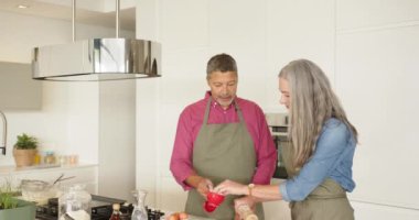 Birlikte yemek pişirmek, çok ırklı yaşlı çift evde modern mutfakta hamur hazırlamak. Aşçılık, takım çalışması, ev hayatı, aşk, aşçılık, ortaklık