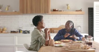 Kahvaltı yapıyorlar, Afro-Amerikan çift mutfak masasında oturmuş yemek yerken sohbet ediyorlar. sohbet, yerli, kahve, sabah, birlikte, yaşam tarzı