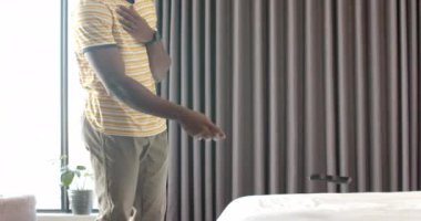 Evde dinlenen Afro-Amerikalı bir adam rahat bir ortamda yatağa uzanıyor. Rahatlama, sağIık, rahatlık, değişmemiş yaşam tarzı.