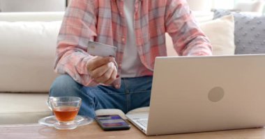 Kredi kartı bulundurmak, dizüstü bilgisayar kullanmak, evden alışveriş yapmak. E-ticaret, çevrimiçi alışveriş, dijital ödeme, işlem, tüketici, kolaylık