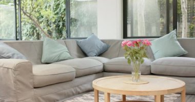 Gri bölmeli kanepesi ve masasında pembe güller olan rahat oturma odası, kopyalama alanı. İç mekan, dekor, ev, mobilya, modern konfor