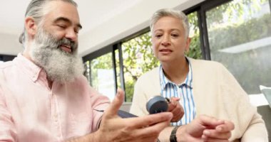 Üst düzey çift evde dijital monitörle kan basıncını ölçüyor ve gülümsüyor. Sağlık, sağlık, izleme, evde bakım, yaşlılar, tıbbi cihaz