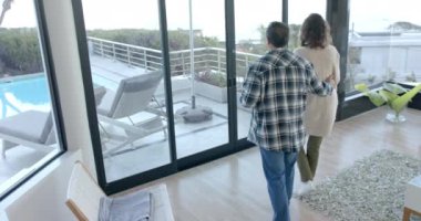 Üst düzey bir çift pencerenin önünde durmuş, havuz başında kahve içip sohbet ediyorlar. Yaşlılar, rahatlama, sabah, yaşam tarzı, emeklilik, kaynaşma