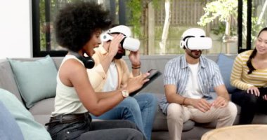 VR kulaklığı takan bir adam kanepeye oturmuş farklı arkadaşlarla gülüyor ve eğleniyor. Teknoloji, sanal gerçeklik, eğlence, arkadaşlık, eğlence, birliktelik.