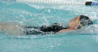 Havuzda yüzen, yüzme şapkası takan ve gözlük takan bir kadın. Yüzme havuzu, fitness, su sporu, eğitim