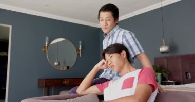 Asyalı baba ve oğul kanepede oturup ciddi ciddi sohbet ediyorlar. Aile, ebeveynlik, bağlılık, iletişim, yaşam tarzı, ev içi