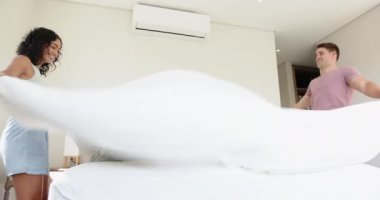 Birlikte yatak yapmak, genç çok ırklı çiftler modern yatak odasında yastık düzenlemek, evde. ev, yaşam tarzı, yerli, ilişki, takım çalışması, birliktelik