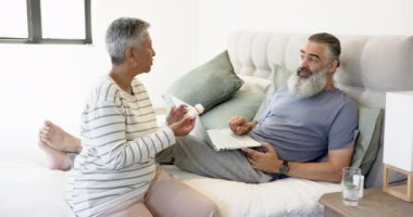 Üst düzey çift yatak odasında dizüstü bilgisayar kullanırken ilaç hakkında konuşuyor, birlikte dinleniyorlar. Yaşlılar, sağlık hizmetleri, teknoloji, emeklilik, kapalı alan, tartışma