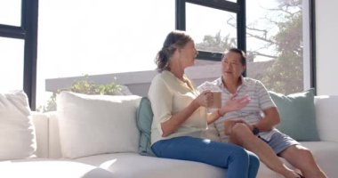 Son sınıf çifti kanepede oturuyor, kahve içiyor, sohbet ediyor, fotokopi çekiyor. Yaşlılık, rahatlama, mutluluk, birliktelik, bağlanma, yaşam tarzı, değişmemiş, yavaş çekim